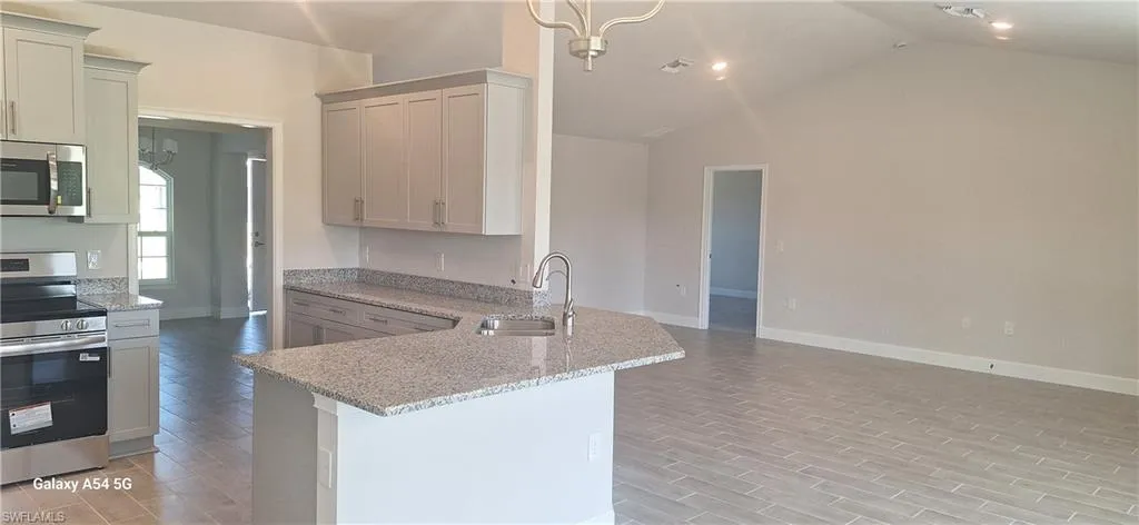 Kitchen featuring dishwashing machine, light stone counters, and a peninsula
