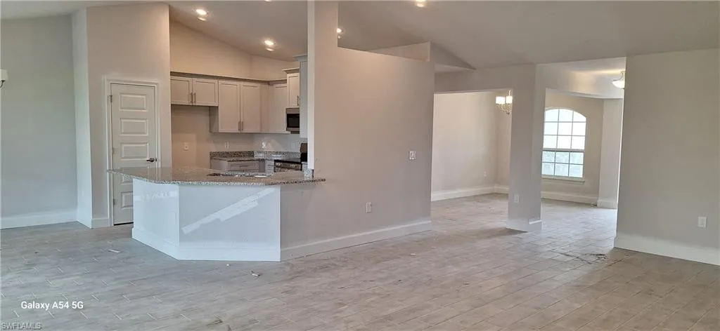 Unfurnished dining area featuring vaulted ceiling, light wood-style flooring, and a chandelier