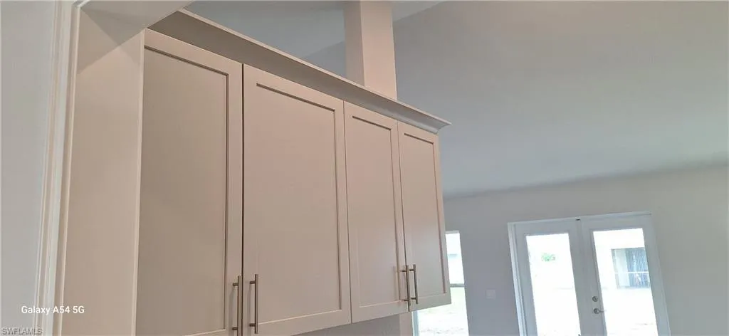 Kitchen with light stone countertops, vaulted ceiling, light wood finished floors, stainless steel microwave, and a peninsula
