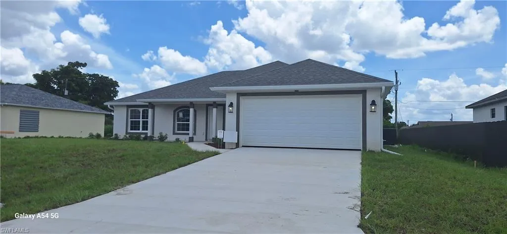 Ranch-style home featuring concrete driveway, a front yard, roof with shingles, an attached garage, and stucco siding