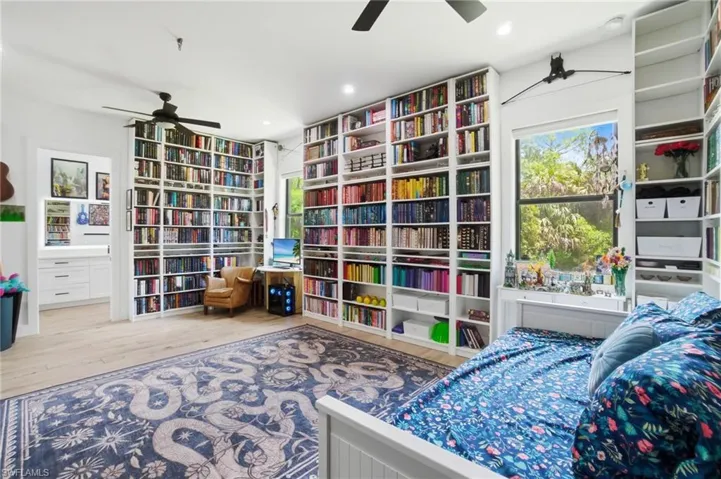 Room featuring extensive built-in shelving, wood-finish flooring, and a ceiling fan