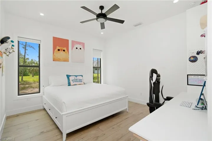 Bright bedroom featuring wood-finish flooring, a contemporary ceiling fan, and recessed lighting