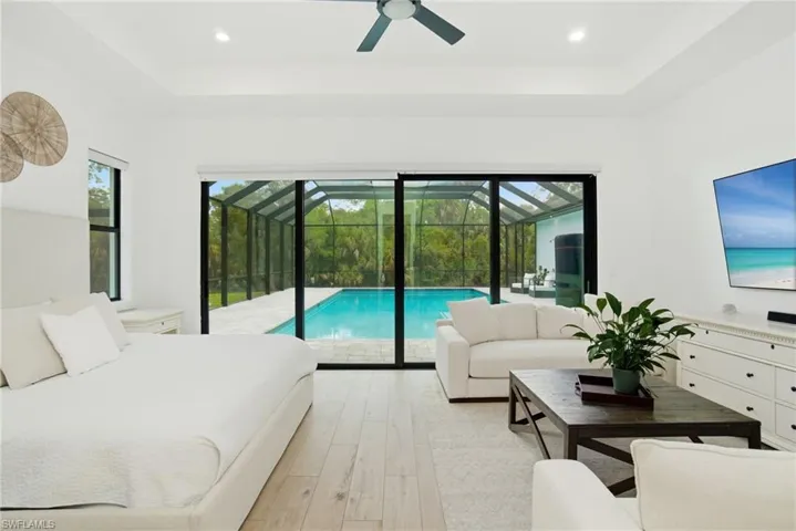 Spacious interior room featuring light wood-finish flooring, a tray ceiling with recessed lighting, and a ceiling fan