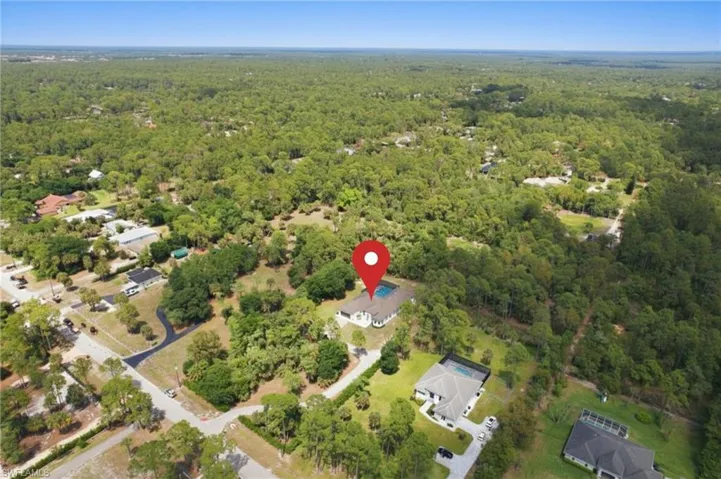 Aerial perspective showcasing a single-story residence with a screened pool enclosure