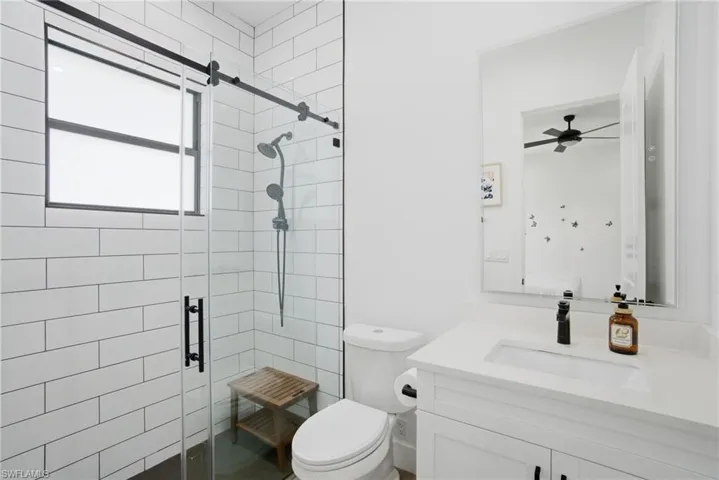 White subway tile shower with a clear glass enclosure, matte black fixtures, and a window