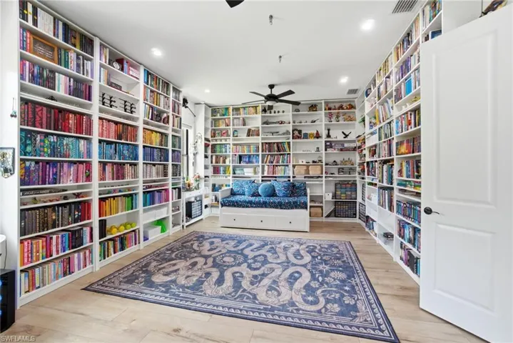 Room featuring extensive built-in shelving, wood-finish flooring, and a ceiling fan