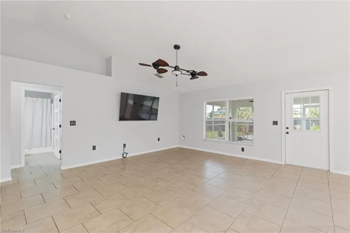 Unfurnished living room featuring ceiling fan, high vaulted ceiling, and light tile patterned flooring
