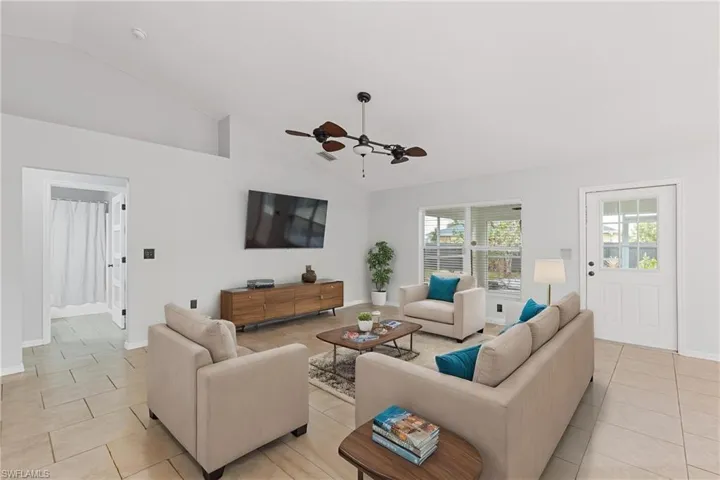 Living room featuring light tile patterned floors, high vaulted ceiling, a healthy amount of sunlight, and ceiling fan