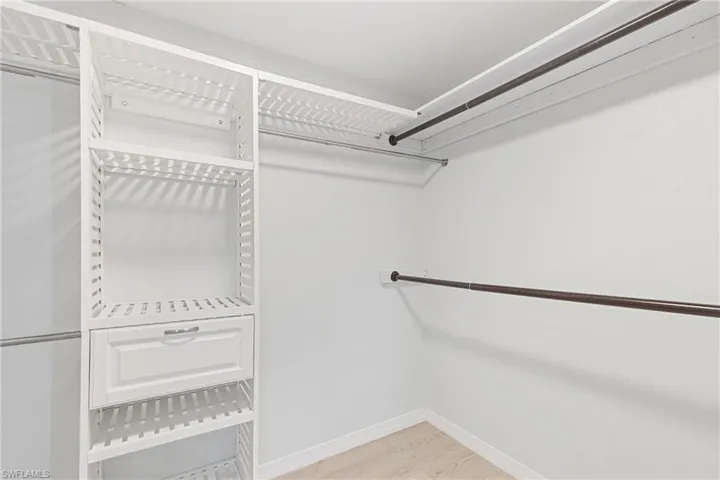 Walk in closet with light hardwood / wood-style flooring