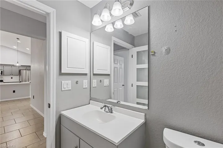 Bathroom with vanity, toilet, tile patterned floors, and lofted ceiling