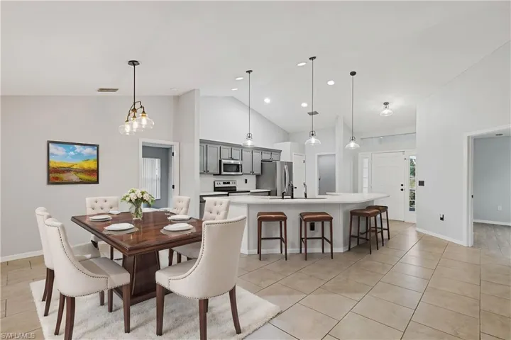 Tiled dining space featuring high vaulted ceiling