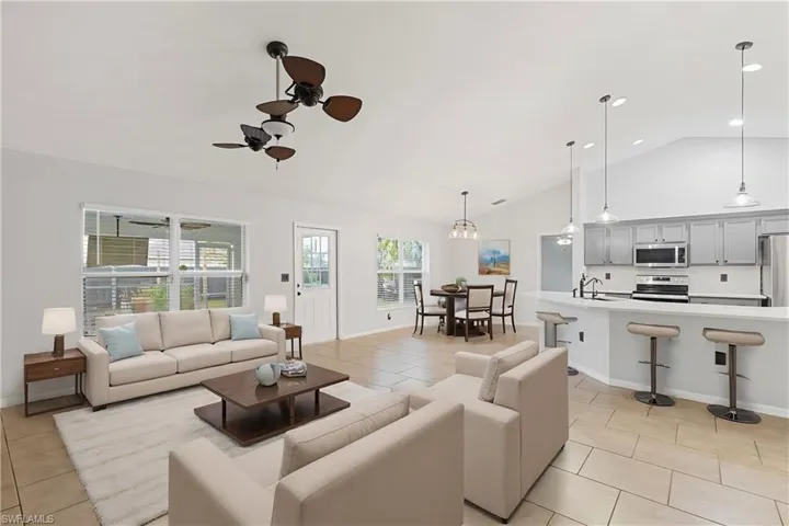 Tiled living room with sink, ceiling fan, and vaulted ceiling