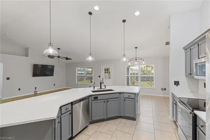 Kitchen with lofted ceiling, sink, appliances with stainless steel finishes, and hanging light fixtures