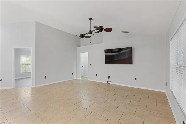Unfurnished living room with ceiling fan, high vaulted ceiling, and light tile patterned flooring