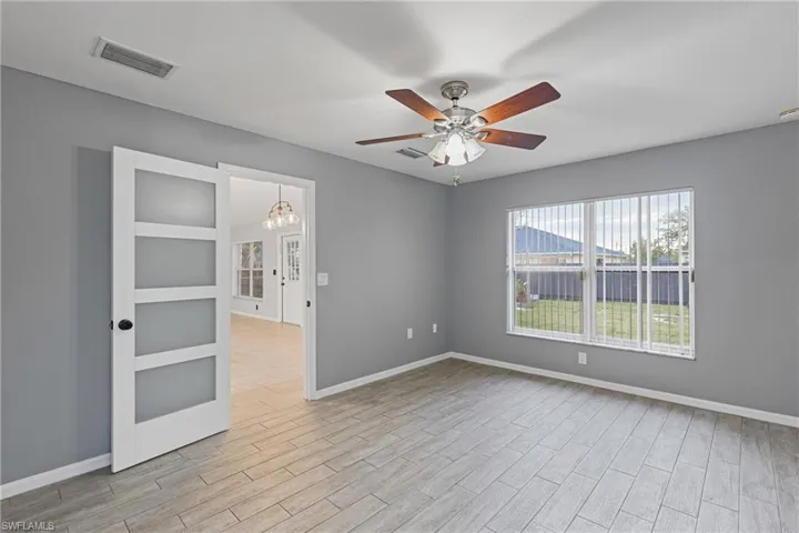 Unfurnished room with light wood-type flooring and ceiling fan with notable chandelier
