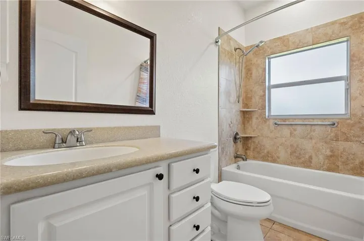 Full bathroom with tiled shower / bath, vanity, toilet, and tile patterned flooring