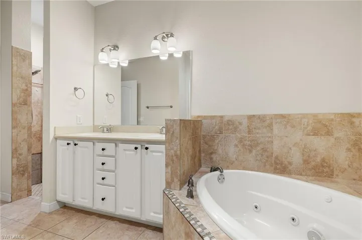 Bathroom with tile patterned flooring, vanity, and separate shower and tub