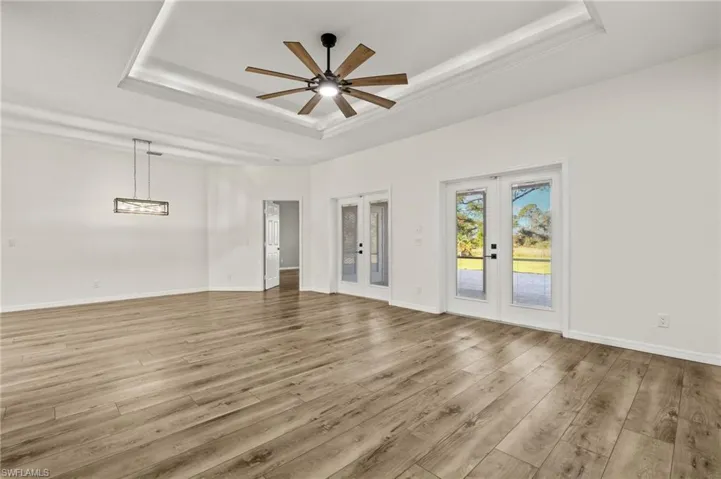 Spare room with light hardwood / wood-style floors, french doors, and a tray ceiling
