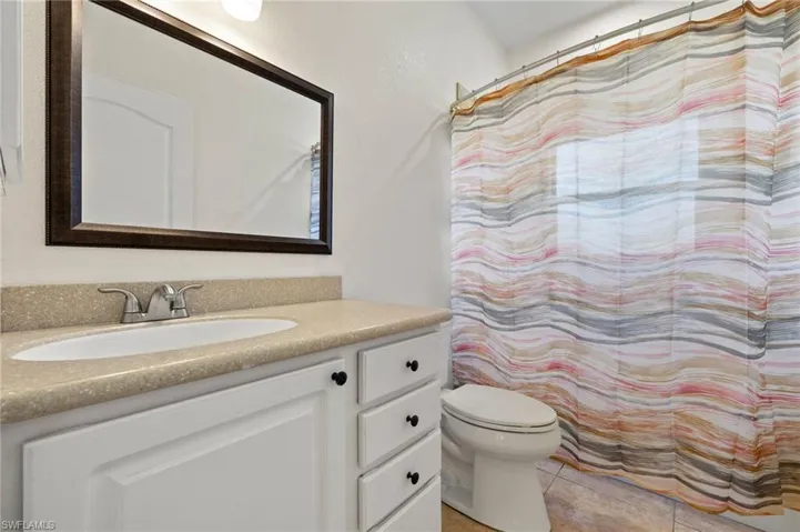 Bathroom with toilet, vanity, and tile patterned floors