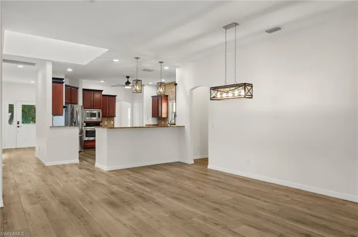 Kitchen featuring kitchen peninsula, light hardwood / wood-style flooring, ceiling fan, pendant lighting, and appliances with stainless steel finishes