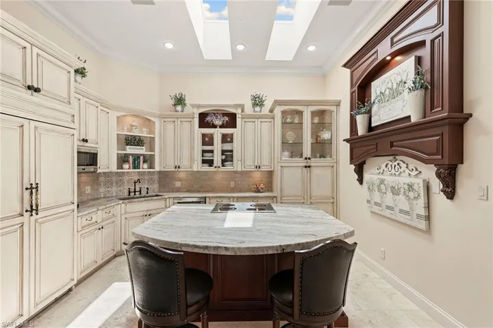 Kitchen featuring cream cabinetry, glass insert cabinets, open shelves, light stone counters, and backsplash