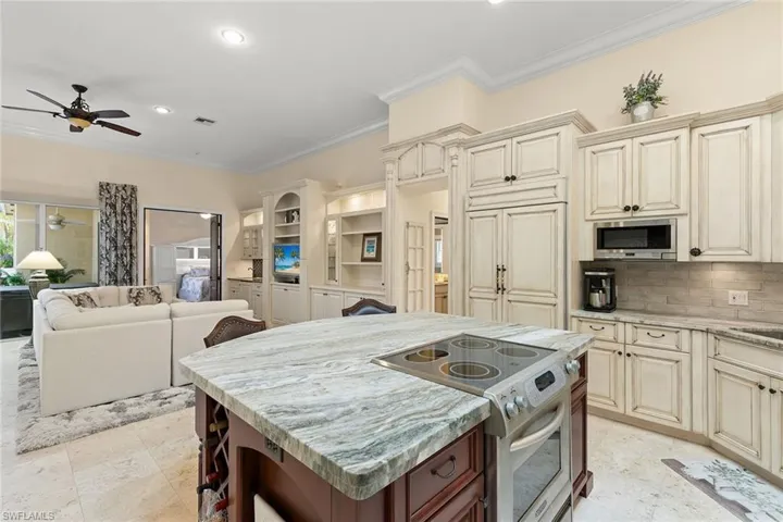 Kitchen featuring cream cabinets, appliances with stainless steel finishes, light stone countertops, crown molding, and a breakfast bar