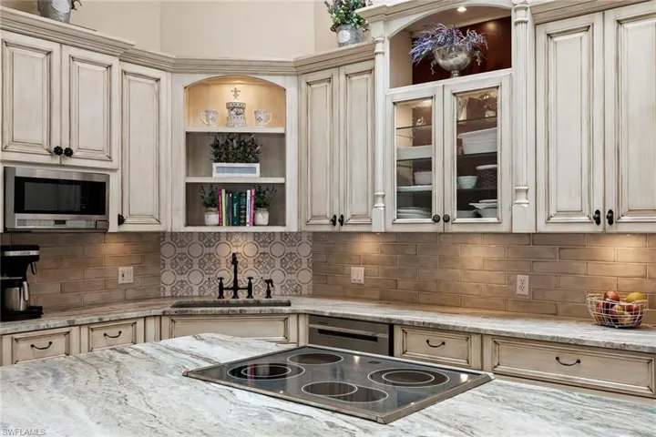 Kitchen featuring cream cabinets, light stone countertops, appliances with stainless steel finishes, and open shelves