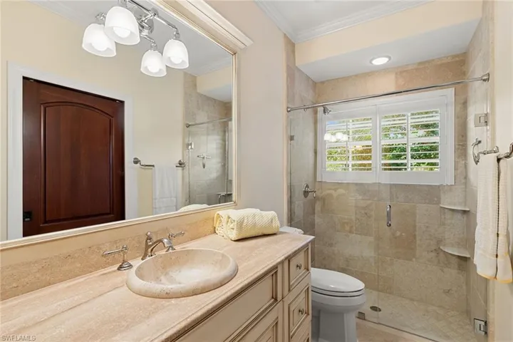 Full bath with a stall shower, vanity, and ornamental molding