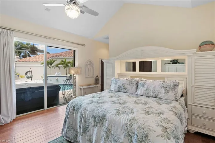Bedroom with access to exterior, wood-type flooring, a ceiling fan, and high vaulted ceiling