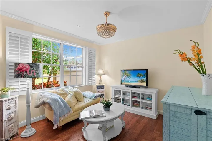 Living room with dark wood-style floors and ornamental molding