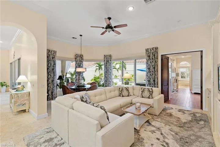 Living area featuring ornamental molding, plenty of natural light, ceiling fan, arched walkways, and recessed lighting
