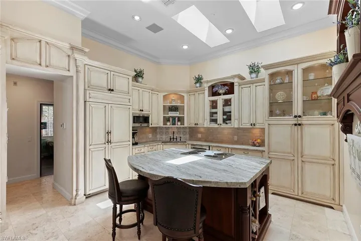 Kitchen with open shelves, crown molding, light stone countertops, a center island, and a breakfast bar