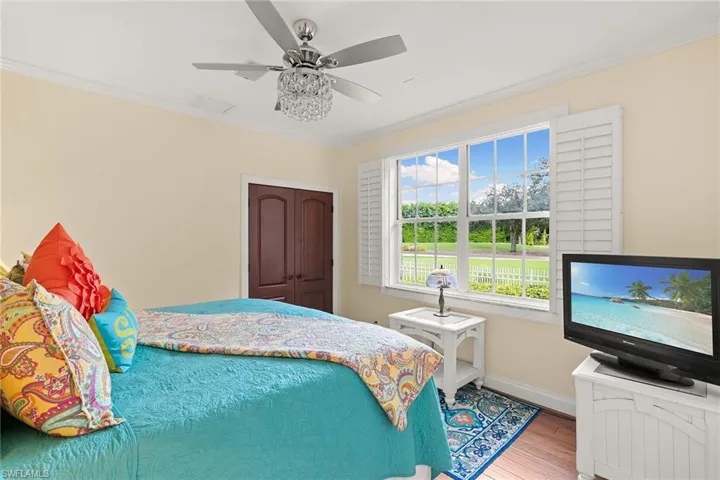 Bedroom with crown molding, wood finished floors, a ceiling fan, and a closet