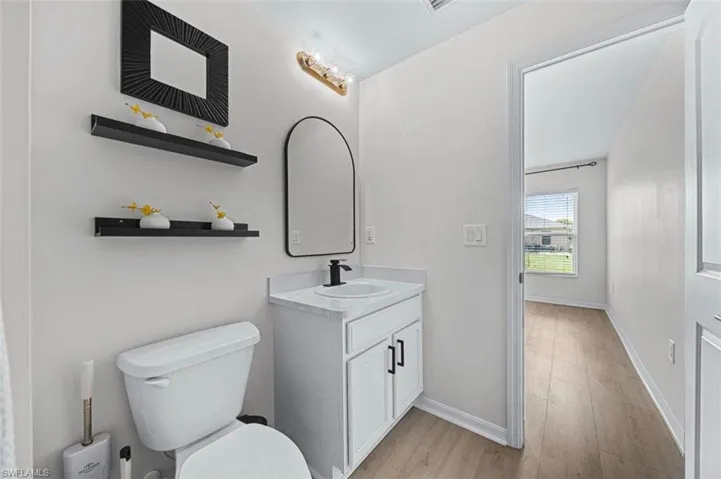 White vanity with a single basin sink, matte black faucet, and white countertop