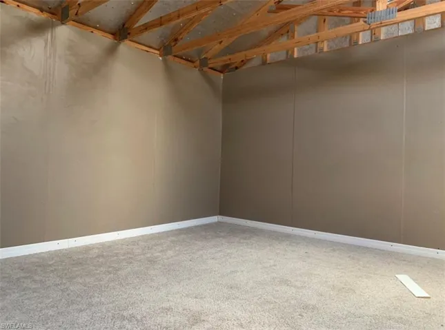 Spare room with baseboards, carpet, and vaulted ceiling
