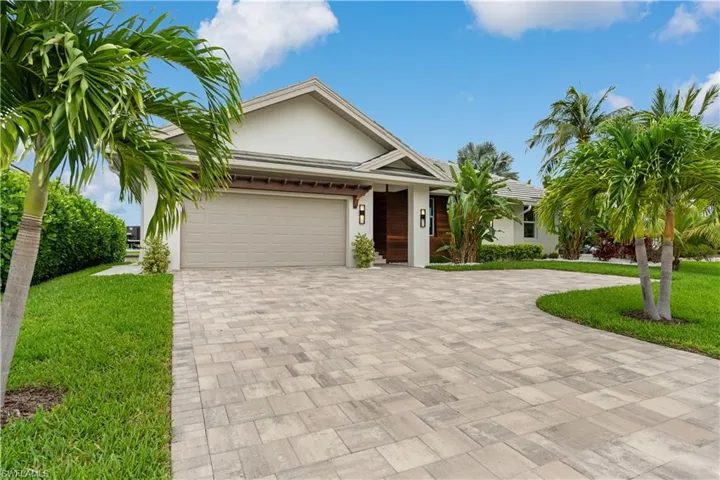 Exterior with stucco, paver driveway, and well-maintained landscaping.