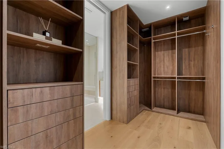 Primary walk-in closet features custom cabinetry.