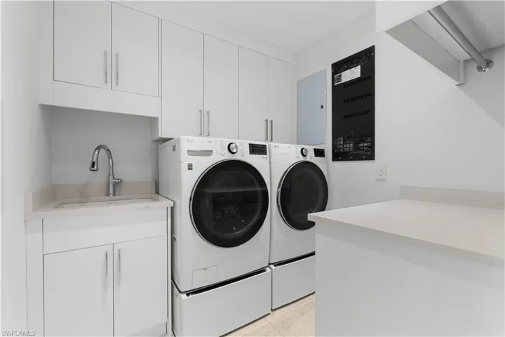 Laundry features front loading washer & dryer, custom cabinets, sink, and folding area.