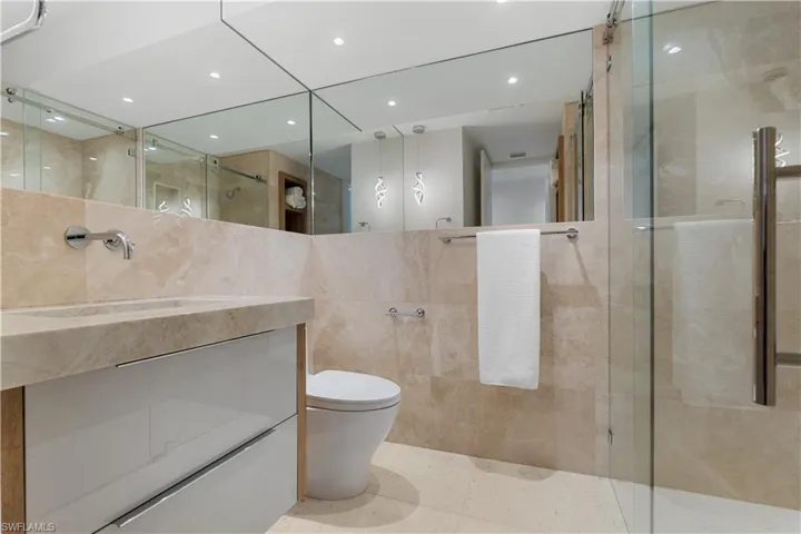 Primary bathroom features wrap around mirrors and floating vanities.