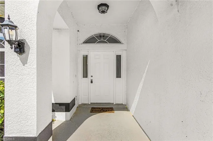 Arched entryway with a recessed light fixture and a wall-mounted coach light