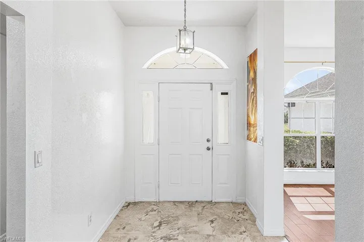 Entryway featuring a decorative pendant light, a transom window, sidelight windows, and stone-finish flooring