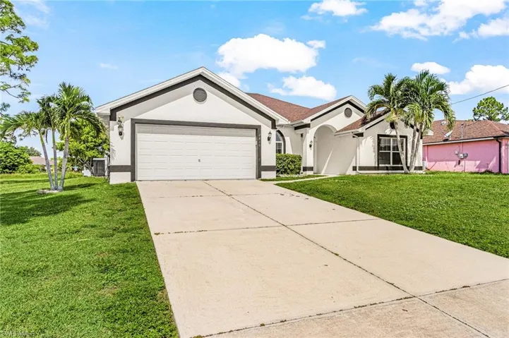 White exterior with dark trim accents, attached garage with a white door, concrete driveway, and a manicured lawn