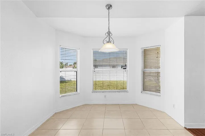 Recessed ceiling with a hanging pendant light fixture, three large windows, and tile flooring