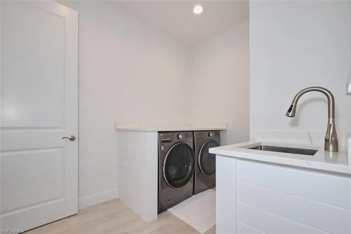 Laundry room with washer and dryer, light hardwood / wood-style flooring, and sink