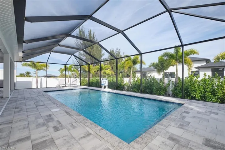 View of swimming pool with screen enclosure and a patio area