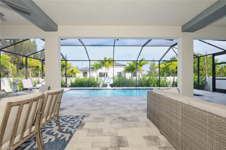 View of pool with outdoor lounge area, screen enclosure, and a patio
