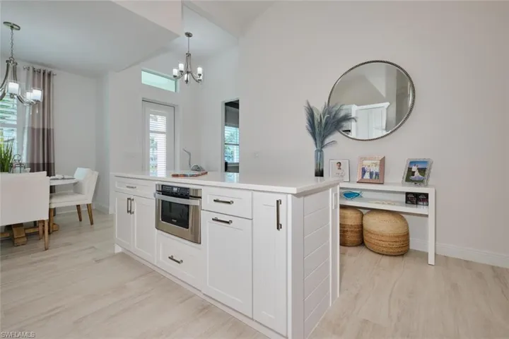 Kitchen featuring white cabinetry, oven, hanging light fixtures, and a kitchen island