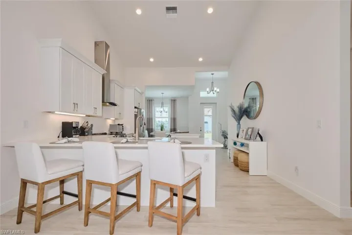 Kitchen featuring a kitchen bar, kitchen peninsula, white cabinetry, and an inviting chandelier