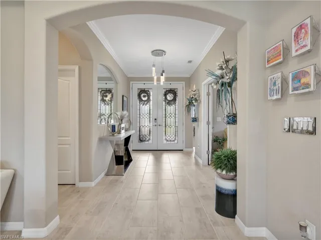 Entrance foyer with crown molding, arched walkways, and french doors