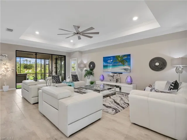 Living area featuring ornamental molding, a raised ceiling, a ceiling fan, and recessed lighting